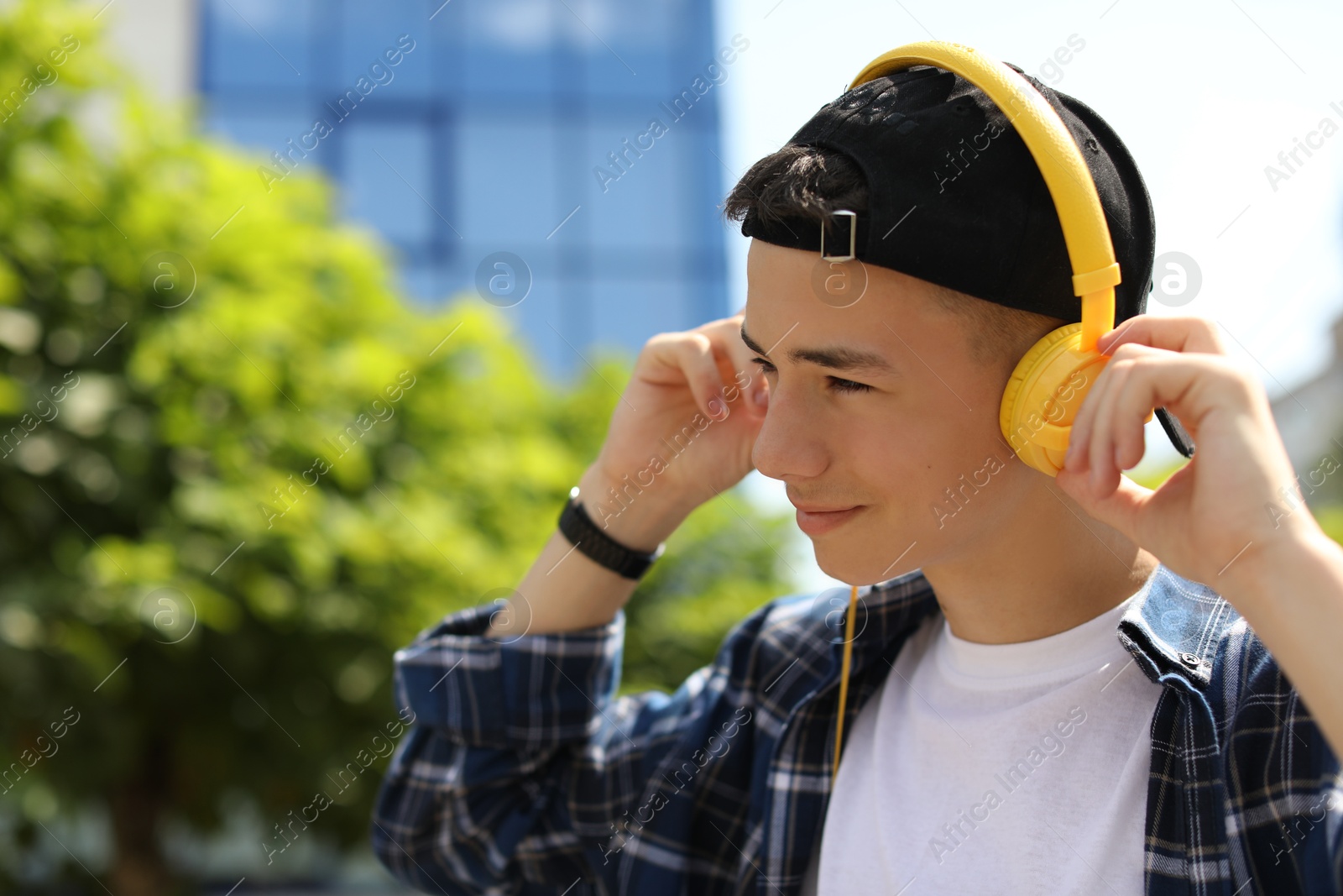 Photo of Portrait of teenage boy with headphones outdoors. Space for text