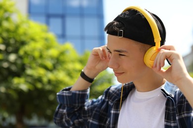 Portrait of teenage boy with headphones outdoors. Space for text