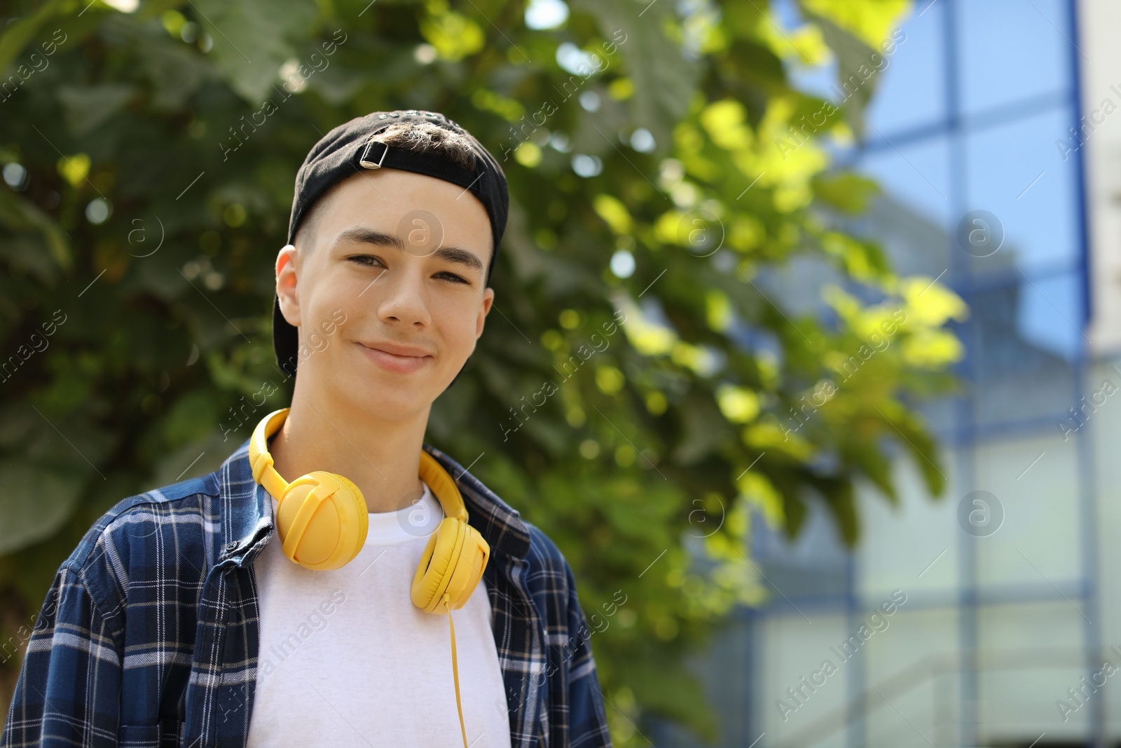 Photo of Portrait of teenage boy with headphones outdoors. Space for text