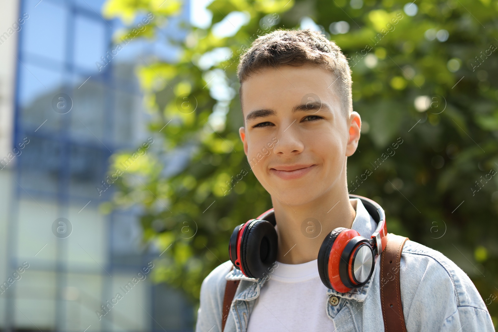 Photo of Portrait of teenage boy with headphones outdoors. Space for text