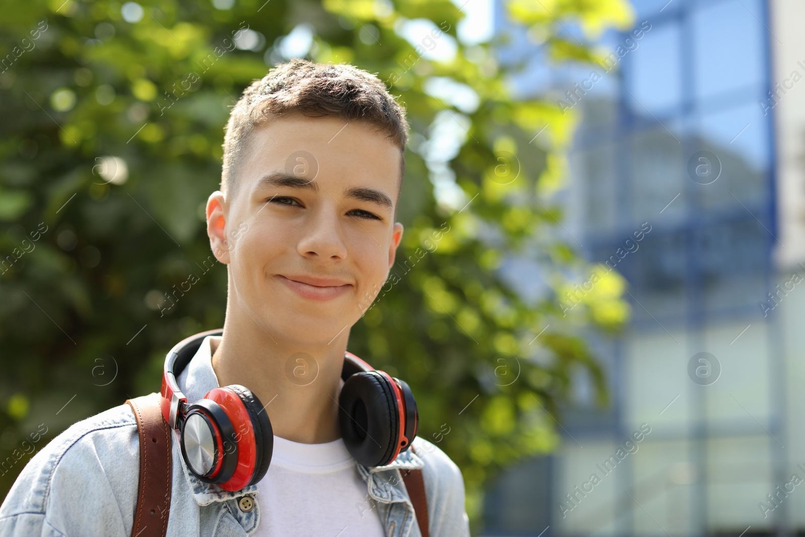 Photo of Portrait of teenage boy with headphones outdoors. Space for text