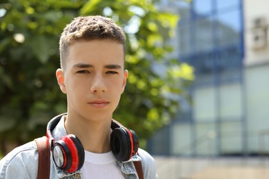 Photo of Portrait of teenage boy with headphones outdoors. Space for text