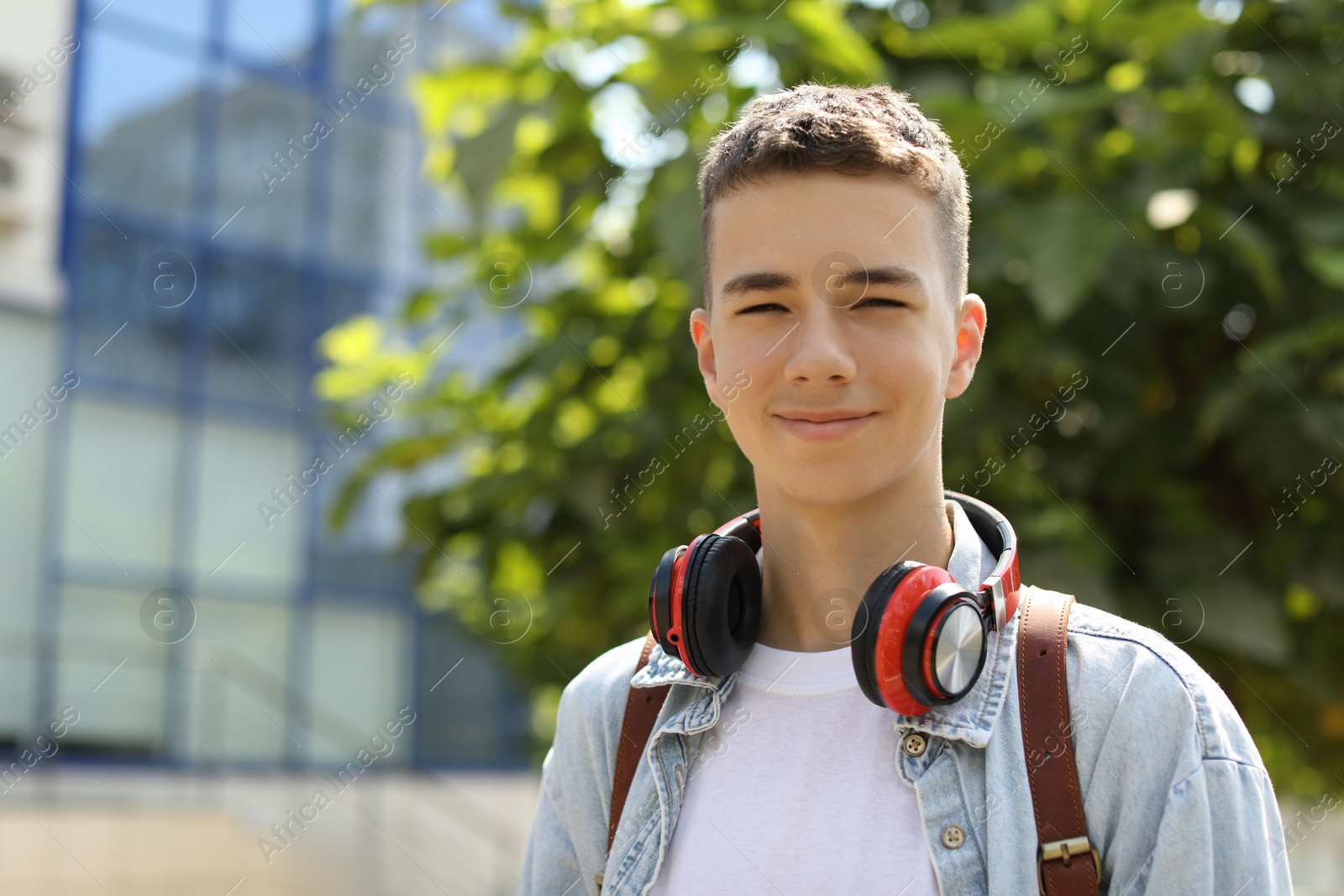 Photo of Portrait of teenage boy with headphones outdoors. Space for text