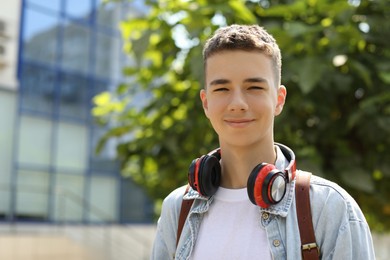 Portrait of teenage boy with headphones outdoors. Space for text