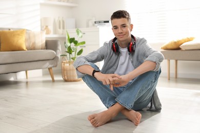 Photo of Full length portrait of teenage boy sitting on floor at home. Space for text