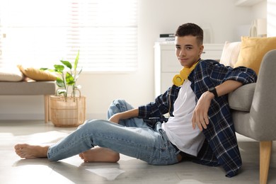 Photo of Full length portrait of teenage boy posing on floor at home. Space for text