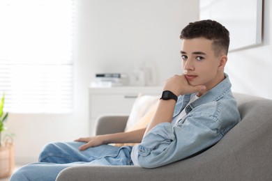 Photo of Portrait of teenage boy on sofa at home. Space for text