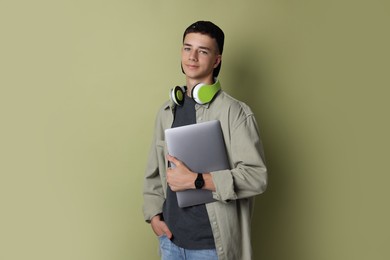 Photo of Portrait of teenage boy with laptop on green background