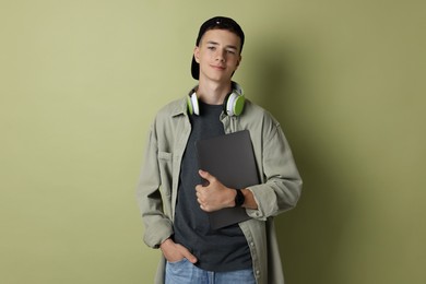 Portrait of teenage boy with laptop on green background