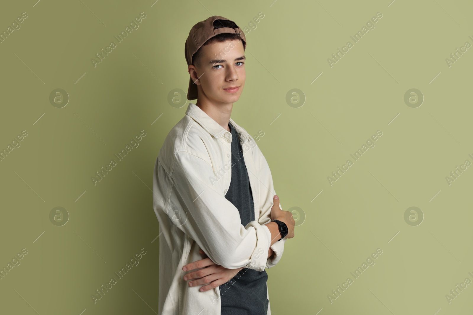 Photo of Portrait of teenage boy with crossed arms on green background