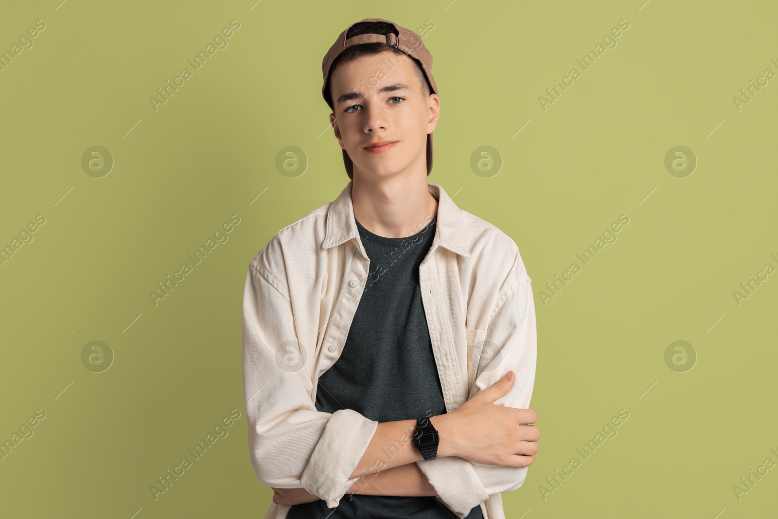 Photo of Portrait of teenage boy with crossed arms on green background