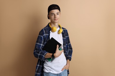 Photo of Portrait of teenage boy with books on dark beige background