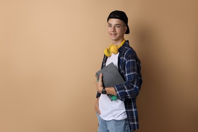 Photo of Portrait of smiling teenage boy with books on dark beige background. Space for text