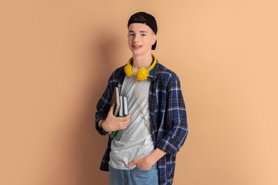 Portrait of smiling teenage boy with books on dark beige background