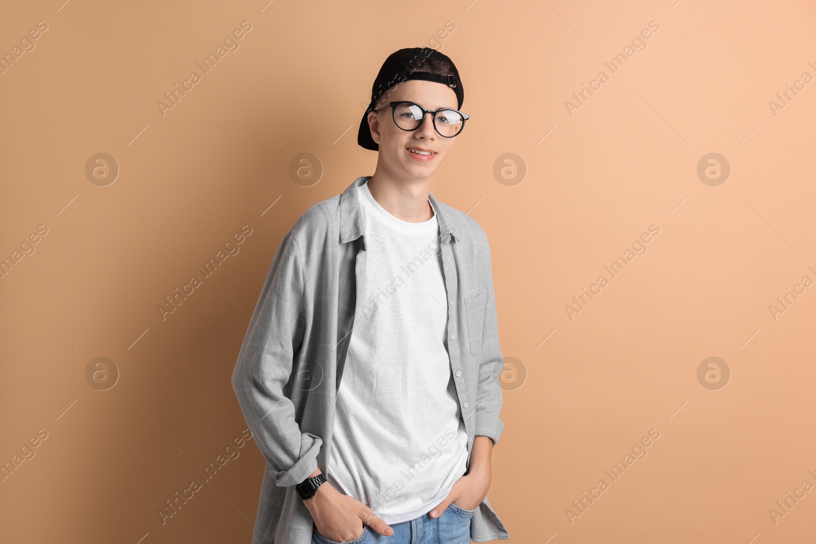 Photo of Portrait of smiling teenage boy on dark beige background