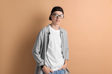 Portrait of smiling teenage boy on dark beige background