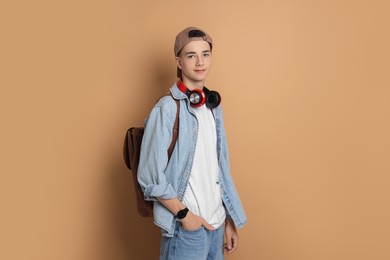 Photo of Portrait of teenage boy with backpack on dark beige background