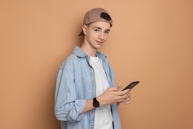 Photo of Portrait of teenage boy with smartphone on dark beige background