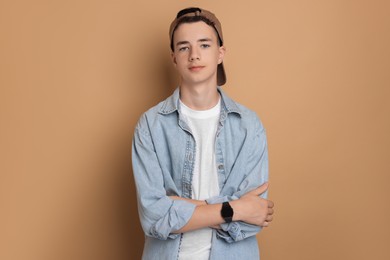 Photo of Portrait of teenage boy with crossed arms on dark beige background