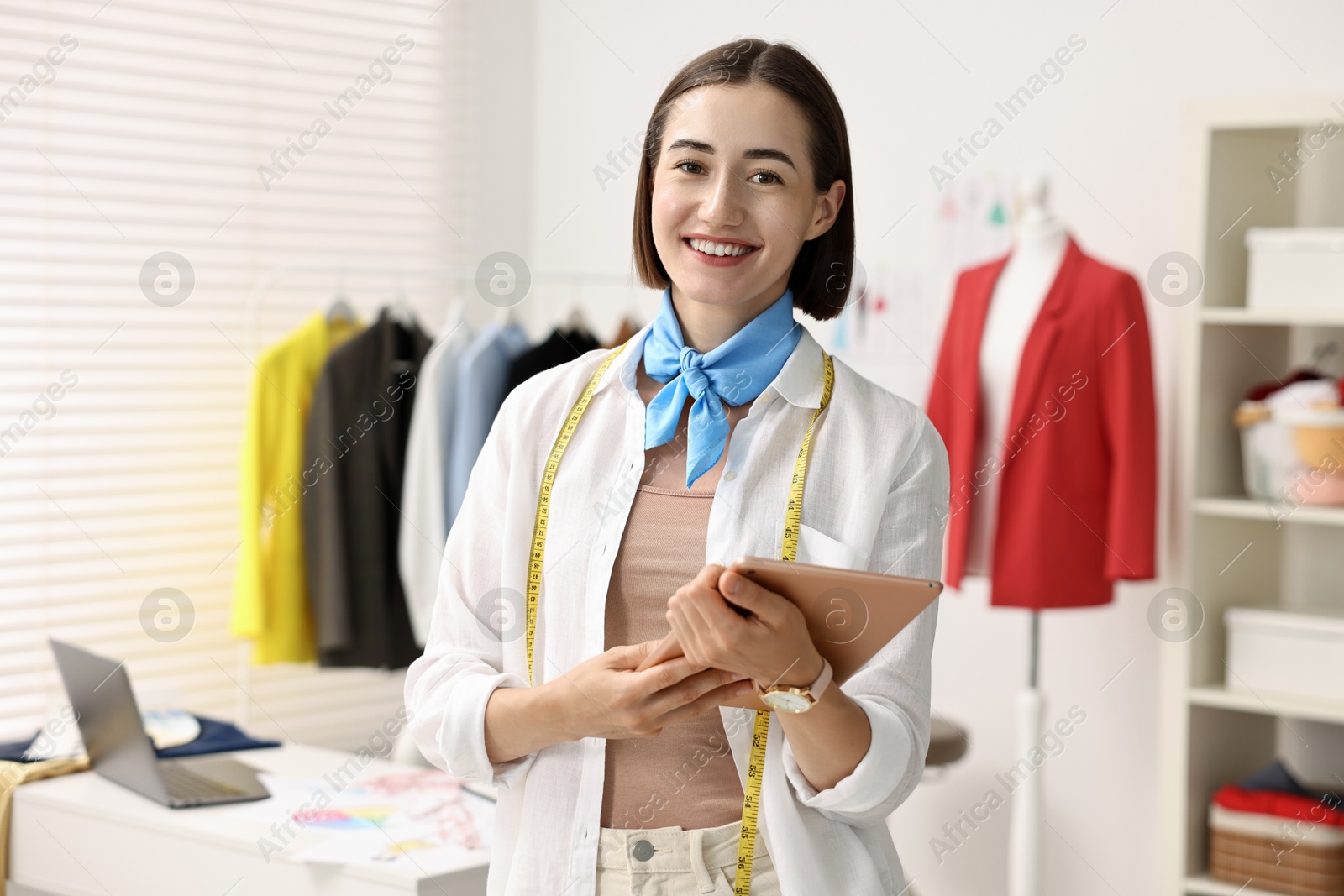 Photo of Happy fashion designer with tablet in workshop