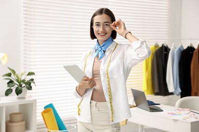 Photo of Happy fashion designer with tablet in workshop