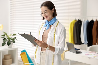 Photo of Fashion designer with clipboard working in workshop