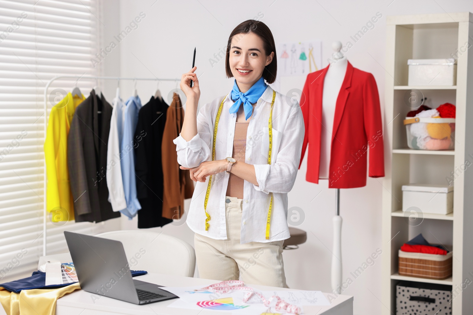 Photo of Fashion designer with pencil near table in workshop