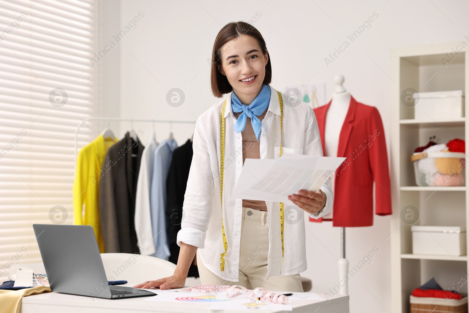 Photo of Fashion designer with paper sheets working in workshop