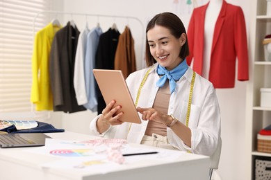 Photo of Fashion designer using tablet at table in workshop