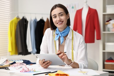 Photo of Fashion designer using tablet at table in workshop