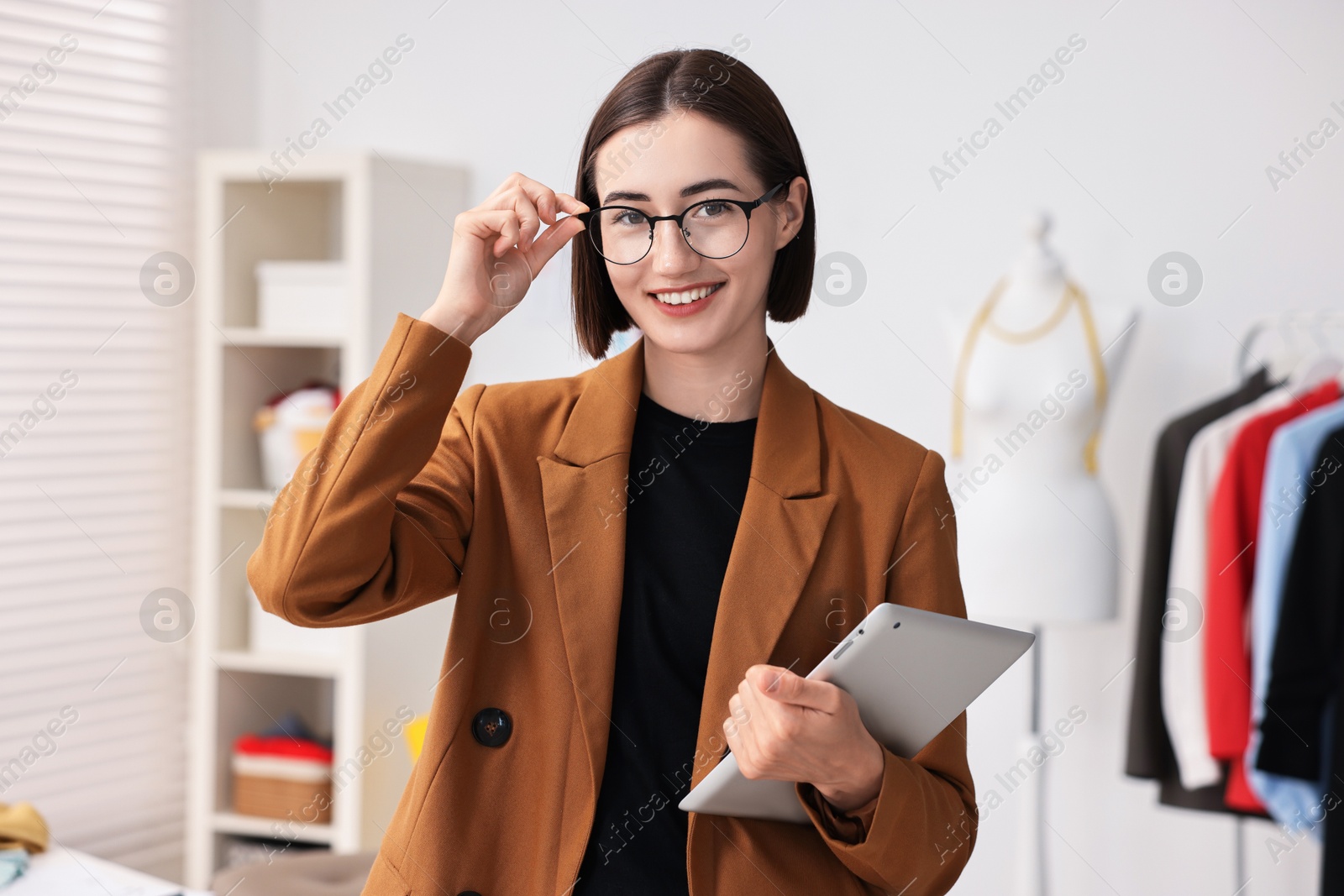 Photo of Happy fashion designer with tablet in workshop