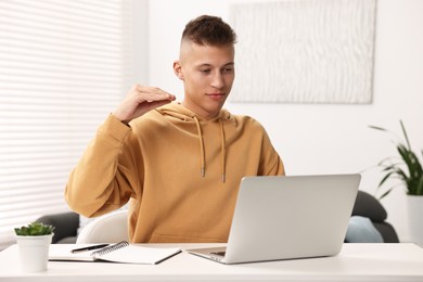 Photo of Young man using sign language during video call indoors