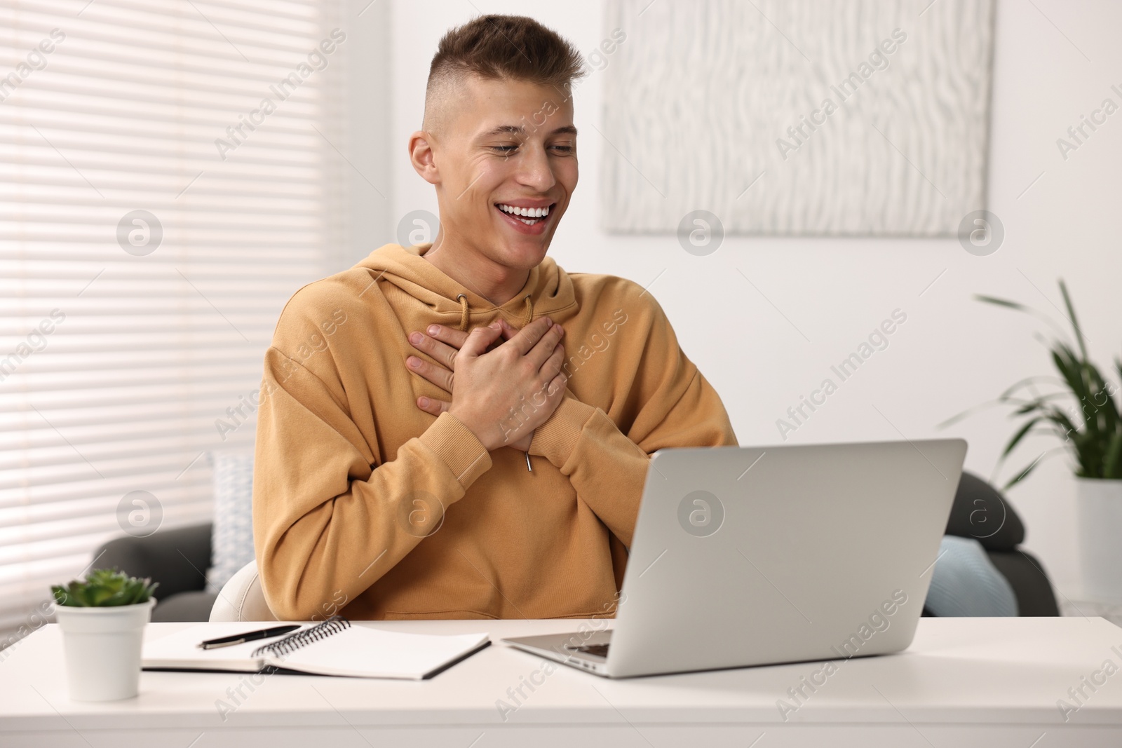 Photo of Young man using sign language during video call indoors