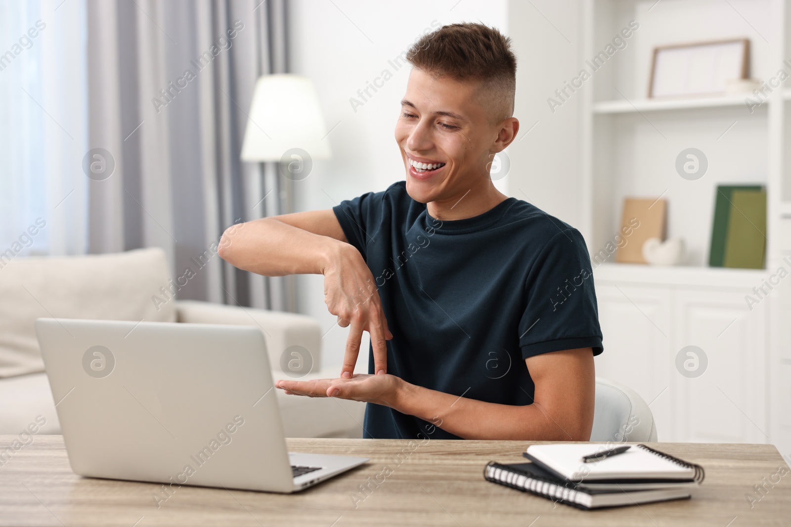 Photo of Young man using sign language during video call indoors