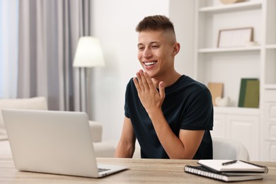 Young man using sign language during video call indoors