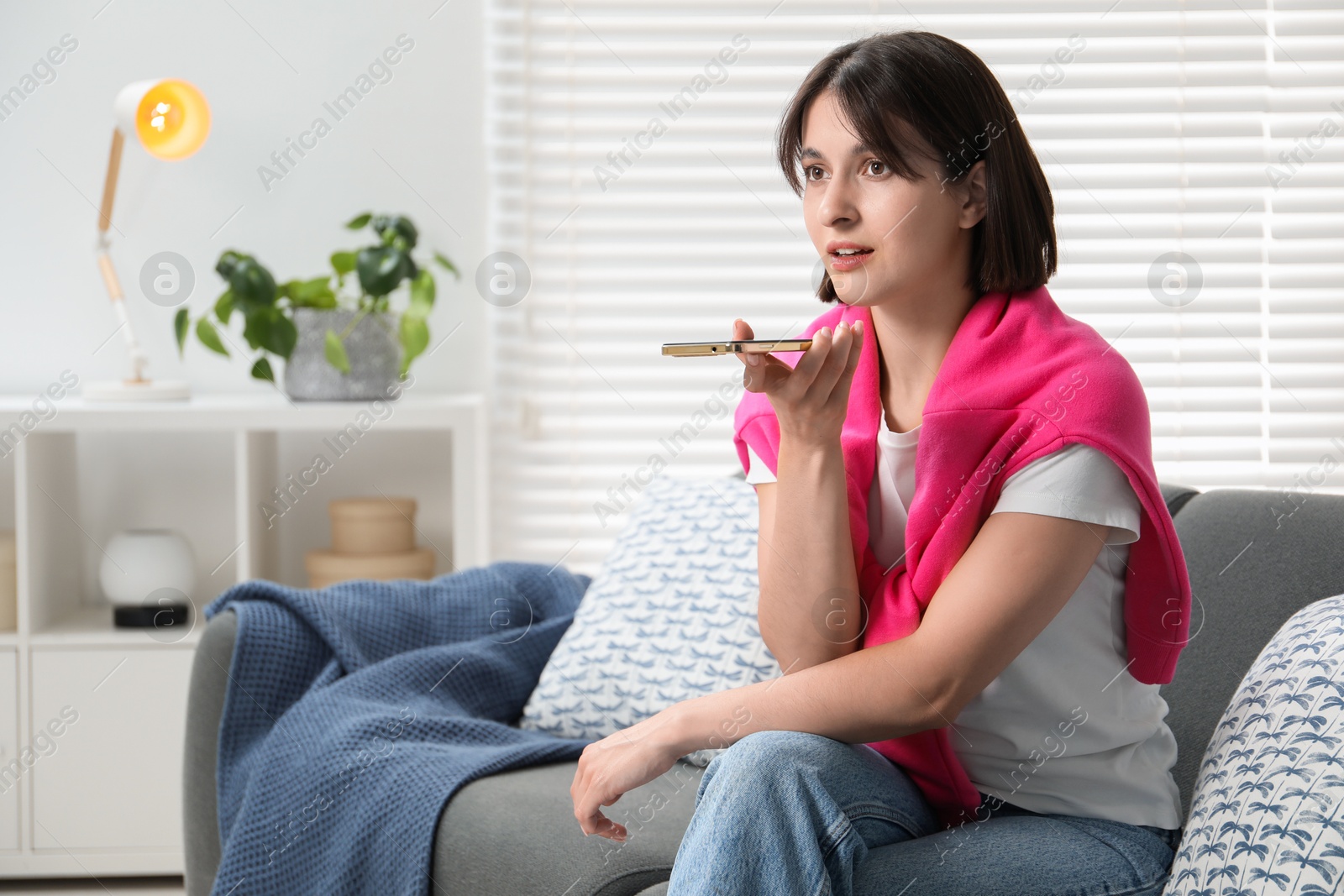 Photo of Beautiful woman recording voice message via smartphone at home