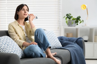 Photo of Beautiful woman with smartphone listening to voice message at home