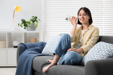 Photo of Beautiful woman with smartphone listening to voice message at home