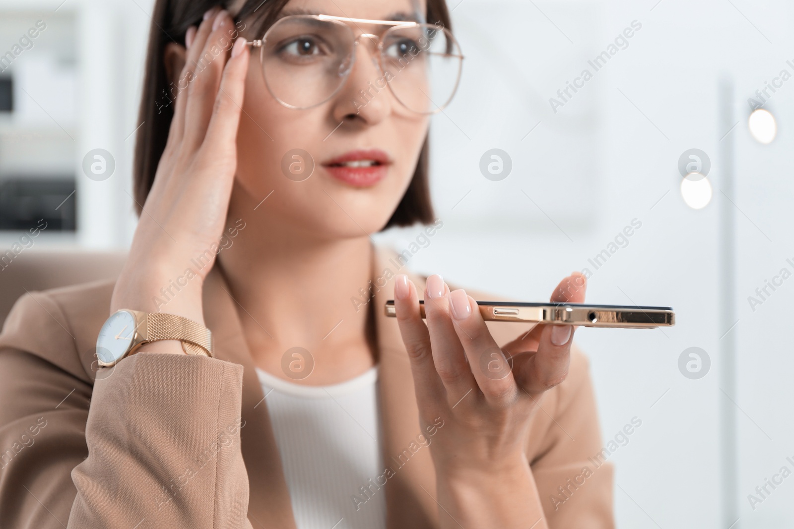 Photo of Beautiful woman recording voice message via smartphone in office, selective focus