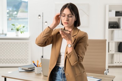 Photo of Beautiful woman recording voice message via smartphone in office