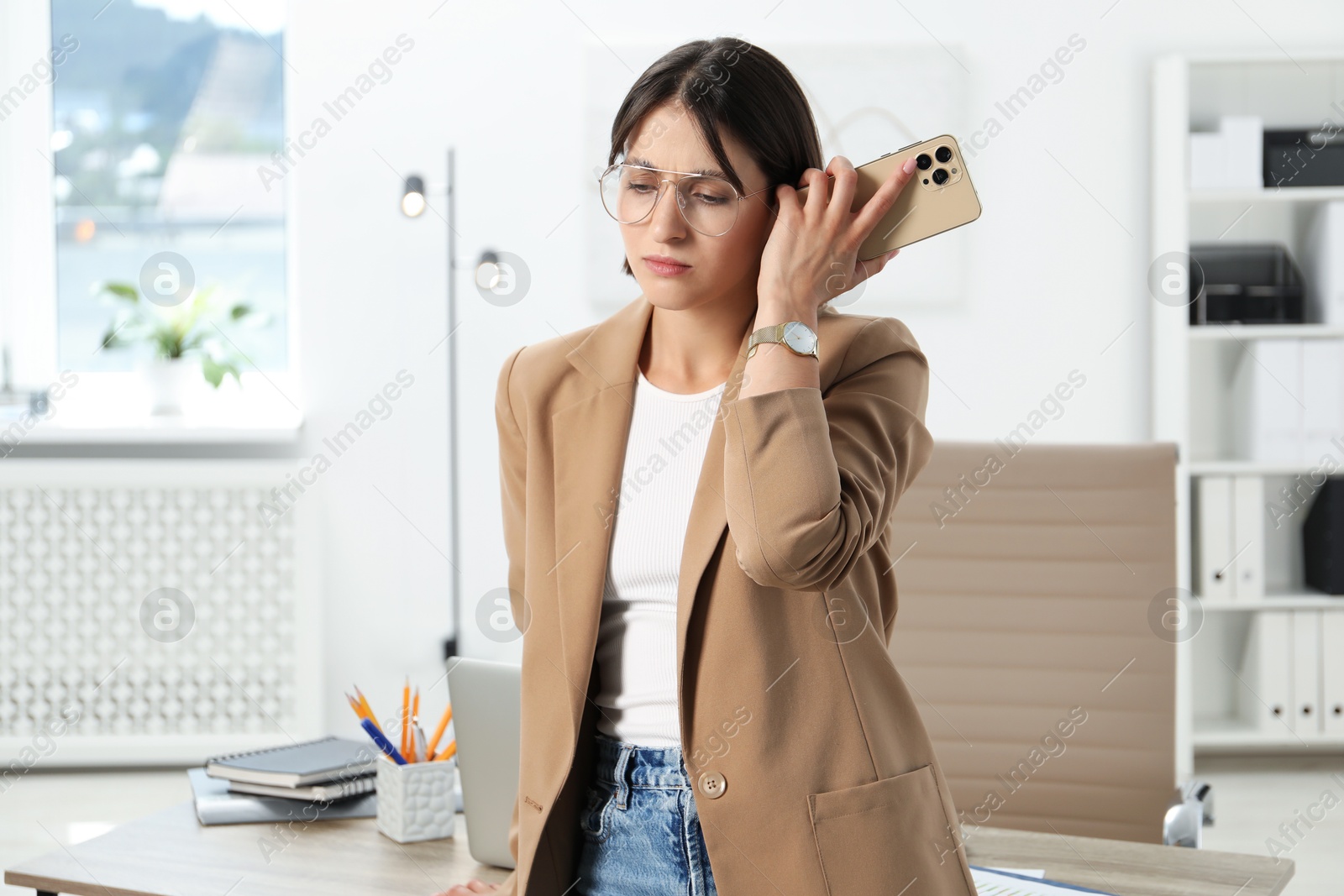 Photo of Beautiful woman with smartphone listening to voice message in office