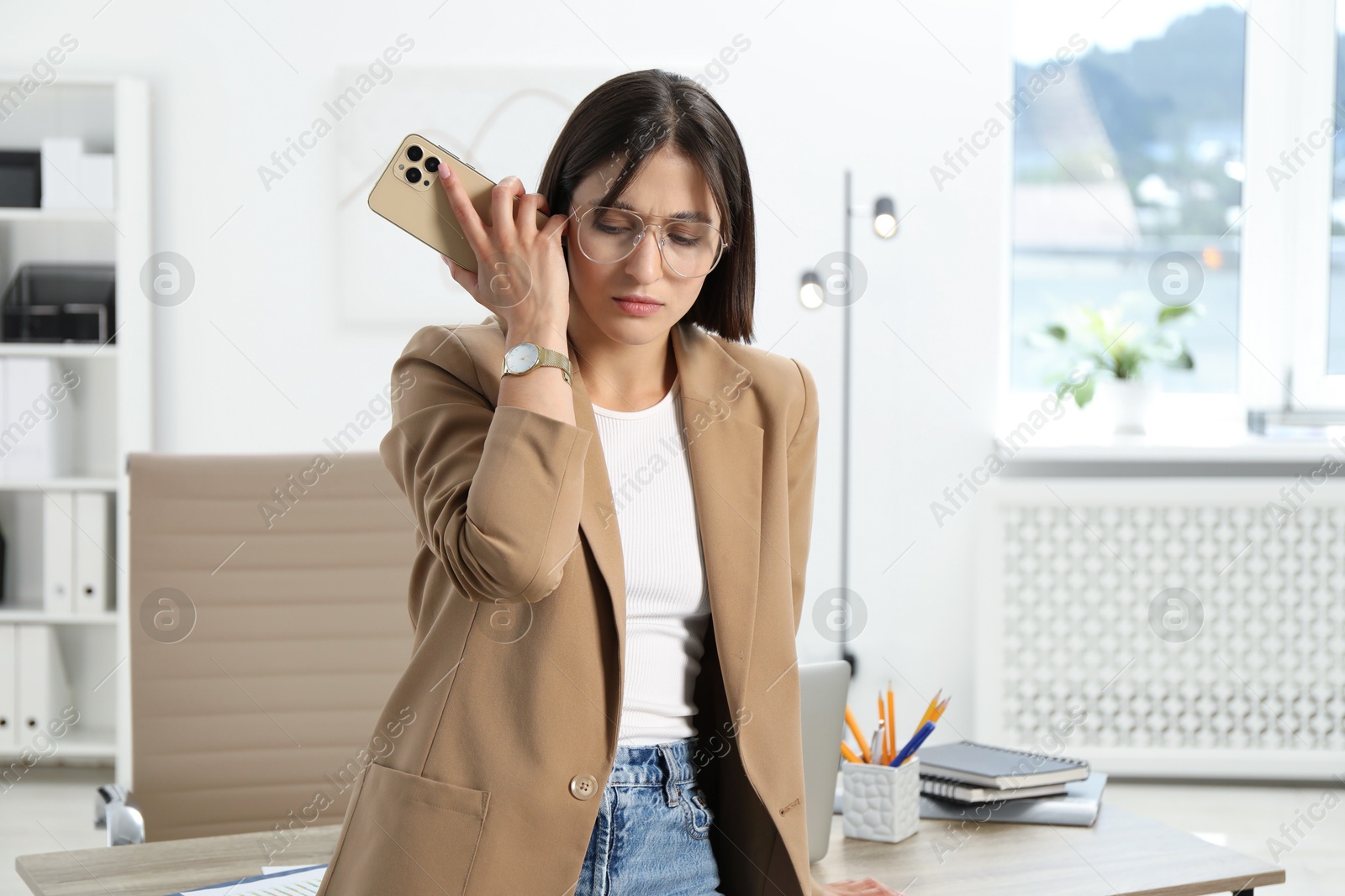 Photo of Beautiful woman with smartphone listening to voice message in office