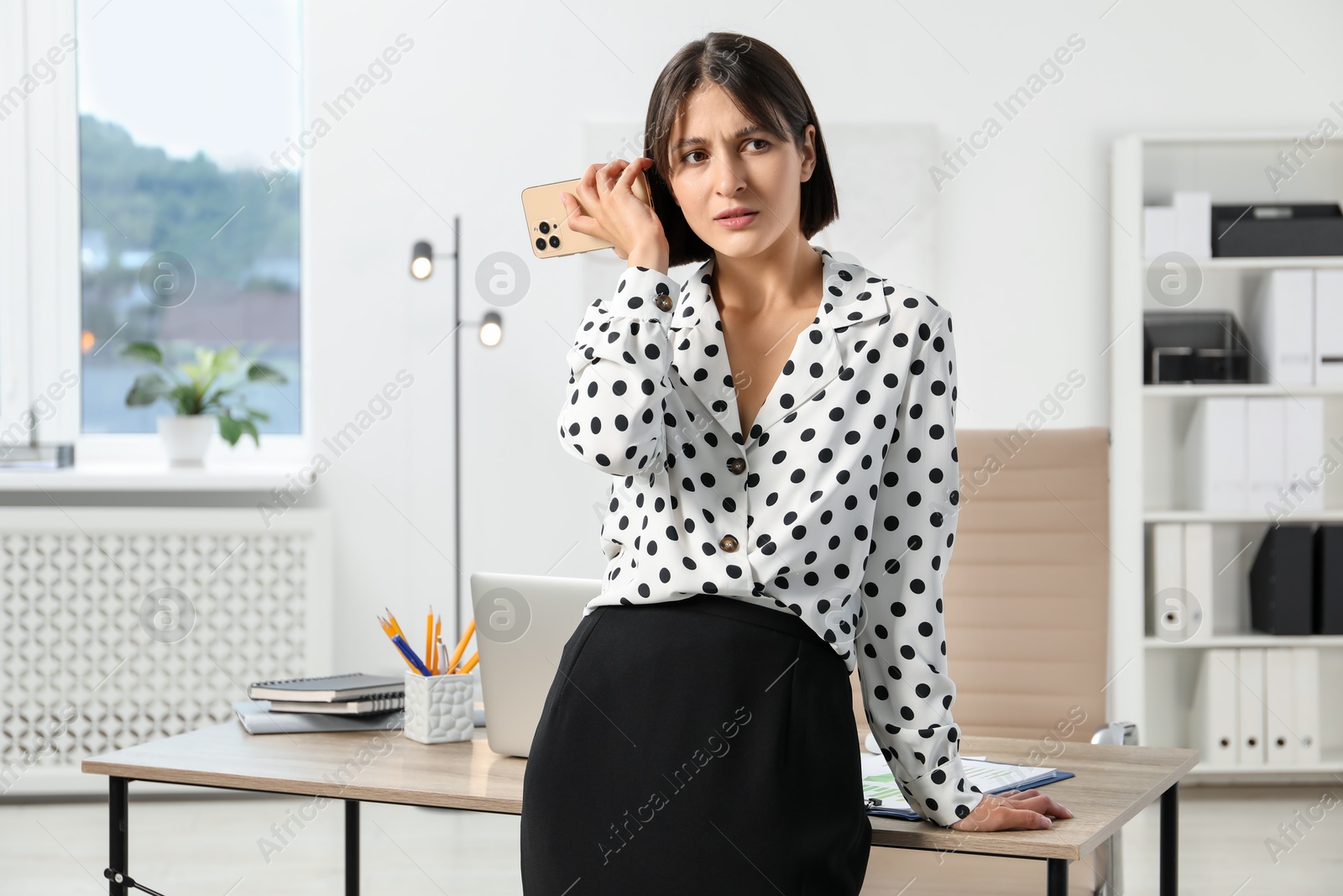 Photo of Beautiful woman with smartphone listening to voice message in office