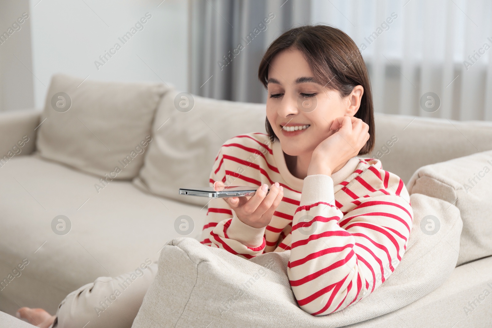 Photo of Beautiful woman recording voice message via smartphone at home