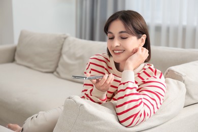 Photo of Beautiful woman recording voice message via smartphone at home