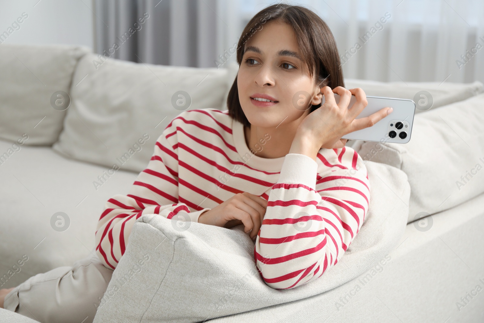 Photo of Beautiful woman with smartphone listening to voice message at home