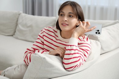 Beautiful woman with smartphone listening to voice message at home