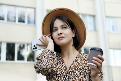 Photo of Beautiful woman with smartphone listening to voice message outdoors, low angle view