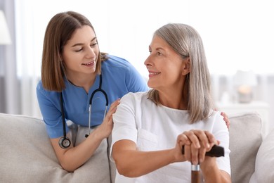 Photo of Smiling healthcare worker supporting senior patient indoors