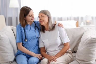 Photo of Smiling healthcare worker supporting senior patient indoors